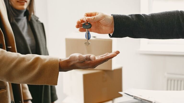 Entrega de las llaves de un piso de alquiler a una inquilina junto a cajas de mudanza